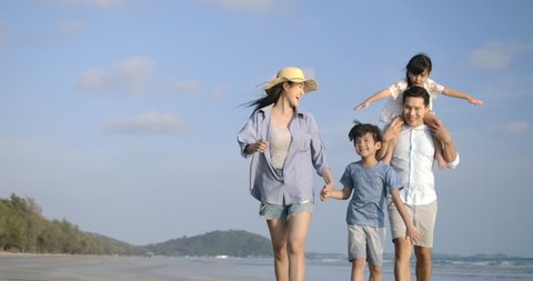 Happy asian family enjoying and walking down the beach on summer vacation. Slow motion. Family, Holiday and Travel concept.