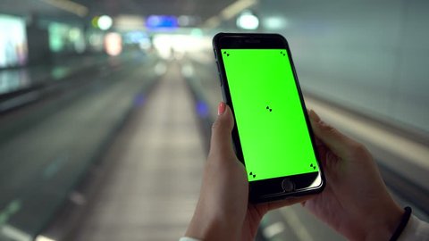 4K, Asian woman show the green screen phone on moving sidewalk at international airport. Using smartphone for one advertisement. Traveller in departure terminal for take the plane to travel-Dan