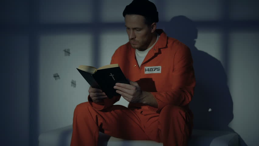 Imprisoned religious male reading bible, convicting in sins, feeling guilty