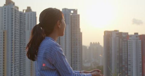 Woman enjoy the view of sunset in city of Hong Kong