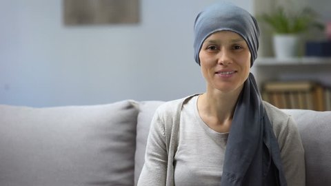 Woman recovering after chemotherapy looking at camera, survivor, background