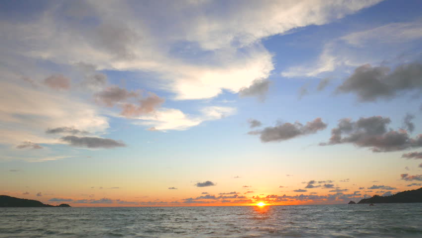 Beautiful evening on the beach with sun going down. A view of sunset and a alluring sky with fluffy clouds.