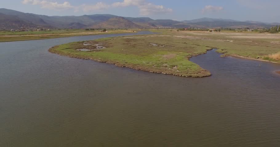 Aerial: A river delta with a road/bridge passing through and some agricultural buildings. Lesbos, Greece.