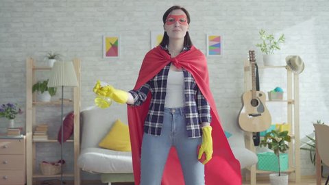 Young woman housewife superhero holding a rag and a spray bottle