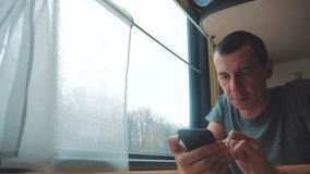 man travel writes smartphone a message social media in the messenger sits on the train by the window traveler concept train railroad journey travel. slow motion video. beautiful from window of a