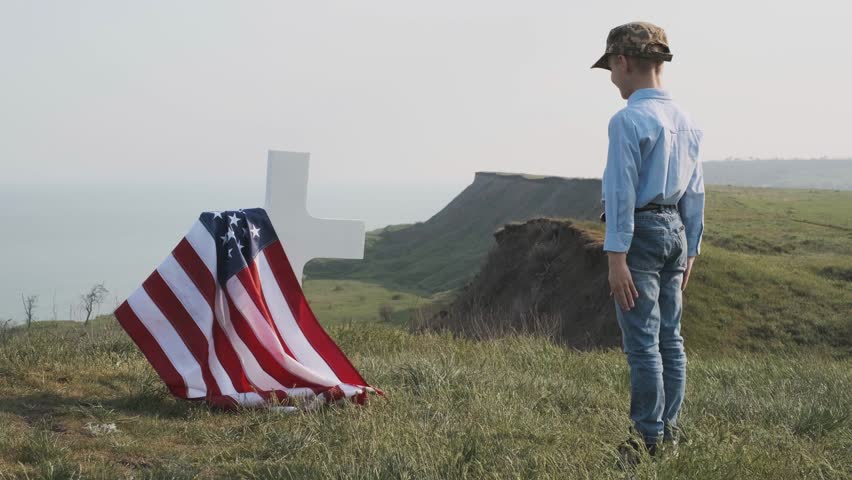 a woman with her son near the grave of her husband an American soldier of the hero of America who died in a hot spot defending the democracy and independence of the United States of America