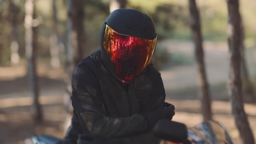 Portrait of a man motorcyclist in a black helmet at sunset. Biker in the forest, color visor | Shutterstock HD Video #1028405411