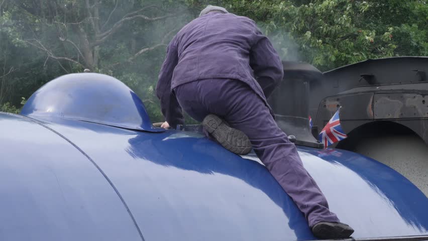 Engineer checking steam release ontop of steam train