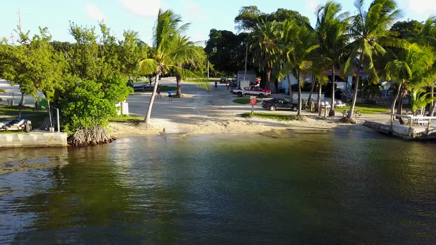 AERIAL: from the ocean, pushing towards and lifting over a small beach in Key Largo, that has the main highway behind it.