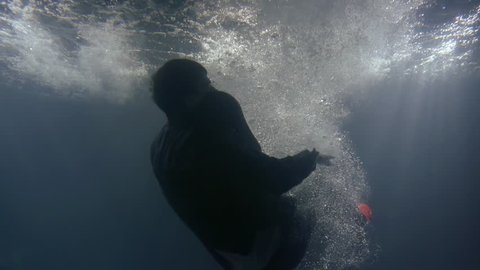 a man in clothes falls back into the water. underwater shooting of a drowning man