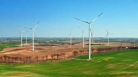 Large wind farms in the field and small tractor in sunny day, aerial view