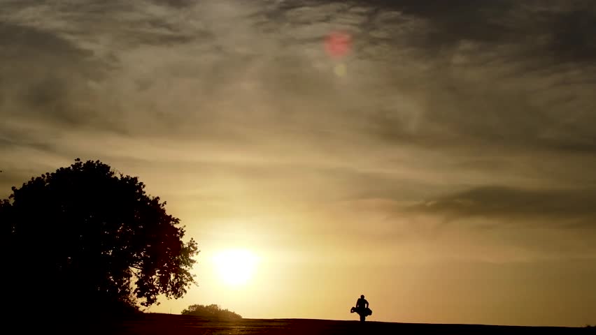 Golf player walking towards the sunset.