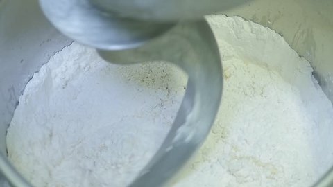 slow motion of dough mixture in speeds up and slows down. Professional mixer combines dough and flour.