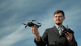 a man with a beard and glasses controls a quadcopter outdoors using a remote control, takes off and lands, portrait,takeoff and landing on the hand