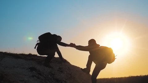 teamwork help business travel silhouette concept. group of tourists lends a helping hand climb the cliffs mountains lifestyle . people climbers climb to the top overcoming hardships the path to