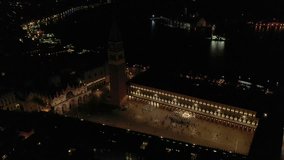 Aerial drone night video of iconic illuminated Saint Mark's square or Piazza San Marco featuring Doge's Palace, Basilica and Campanile, Venice, Italy