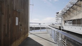 4K video with forward motion of the popular tourist destination Tjuvholmen, located on the tip of Aker brygge, with people enjoying the sun at the beach and on a promenade next to the Oslo fjord.