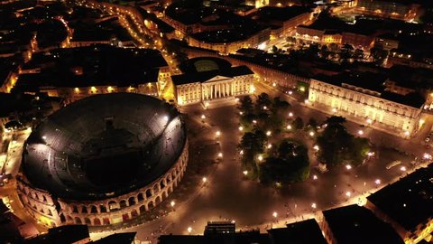 Aerial drone night video from iconic illuminated Arena theatre and City Hall in Bra square of beautiful city of Verona, Lombardy, Italy
