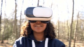 4K video clip of beautiful mixed race African American girl teenager female young woman using virtual reality VR headset in a forest woodland environment