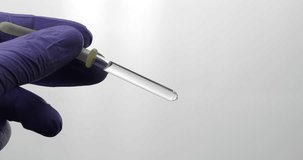 Hand in medical glove drip drop from pipette. Close-up video. Liquid drop over white background. Medical and chemistry laboratory research