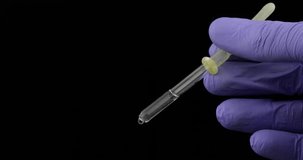 Hand in medical glove drip drop from pipette. Close-up video. Liquid drop over black background. Medical and chemistry laboratory research