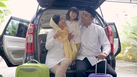 muslim family with kid sitting in the car trunk with suitcase. eid mubarak or idul fitri mudik