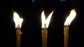 Closeup of yellow candle burn against darkness on black night in the wind as light for life. Dying out the flame. Candle light for spirituality ceremony or worship. 4K video slow motion fps smooth.