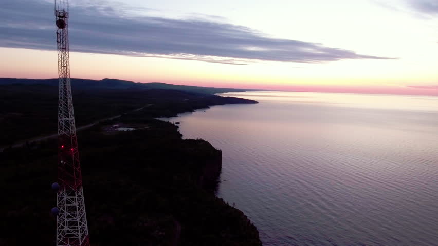 Aerial shot of a telecommunication radio tower at sunrise on lake superior