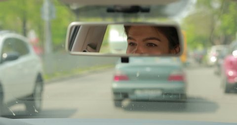 Woman driving car looking at rear view mirror
