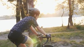 Woman cycling. Girl bicycle training. Young female riding bicycle with river, city and sunset on the background. Cycling concept. Slow motion