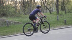 Female cycling. Woman on bike. Girl wearing blue jersey and black helmet riding a bicycle in the park. Road cycling training. Cycling concept. Slow motion