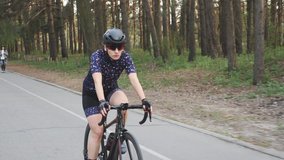 Cycling Woman. Triathlete girl. Focused pro cyclist female riding bicycle in the park. Training concept. Cycling. Slow motion