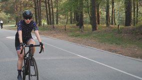 Girl cycling. Woman on bicycle. Girl on black bicycle wearing blue jersey and black helmet riding in the park. Training for cycling race.