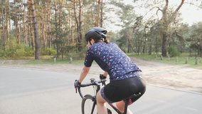 Cycling Woman. Triathlete girl. Female cyclist riding a bicycle in the park. Side follow shot. Cycling training. Slow motion