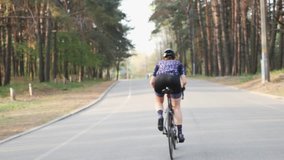 Cycling Woman. Triathlete girl. Triathlete riding bicycle in city park out of the saddle.Triathlon concept. Slow motion