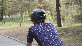 Cycling female on bicycle. Cycling training. Close up shot of female cycling riding bike in a park wearing black helmet and blue jersey. Slow motion
