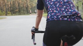 Cycling female on bicycle. Cycling training. Female triathlete cycling girl pedaling bicycle in park. Close up pedals in motion. Triathlon concept. Slow motion