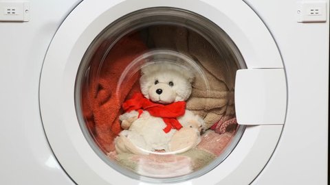 Teddy bear washes in the washing machine. Closeup.