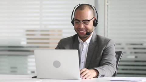 Smiling african american businessman manager talking by video conference call looking at laptop wearing headset, customers service support agent consult client on computer by business teleconference