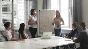 Two diverse female speakers coaches give business presentation on flip chart at corporate training in boardroom, professional team consult clients instruct workers group in teamwork at office meeting - Powered by Shutterstock - Get 15% off with code: PIKWIZARD15