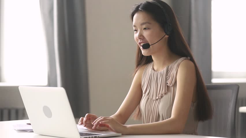 Asian business woman receptionist wear headset consulting customer looking at laptop talking with client in online computer chat, young korean helpline operator secretary make conference video call | Shutterstock HD Video #1028495414