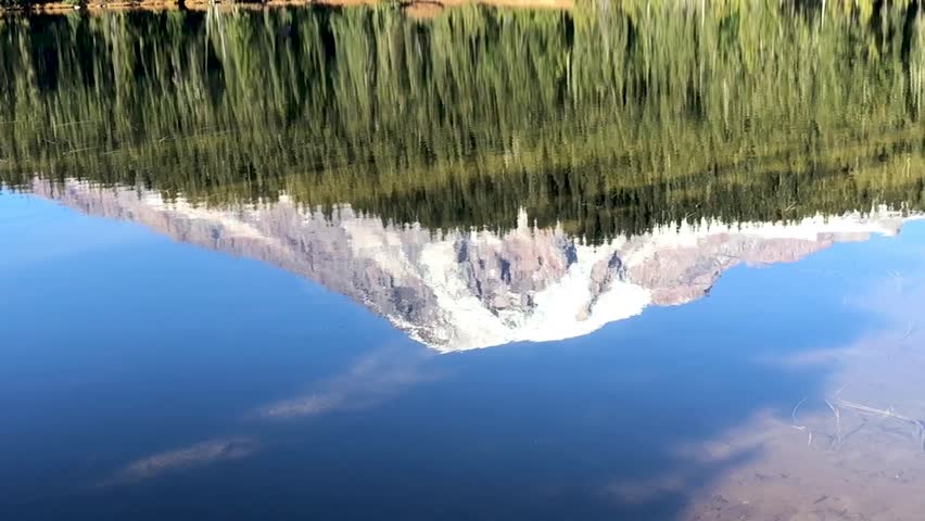 Mount Rainier in Washington State United States reflected from a lake. A stone is thrown into water and creates ripples that disturb the calm waters. Taken in Slow Motion