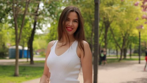 Pretty brunette woman with pink lips walking in a park