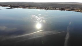 4k drone video of the sun reflecting of a dark blue lake.
