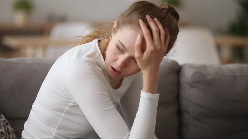 Upset woman sitting on couch alone remembers about quarrel with boyfriend feels offended desperate outraged, restless girl having problems in personal life suffers break up, misunderstanding in family | Shutterstock HD Video #1028517140
