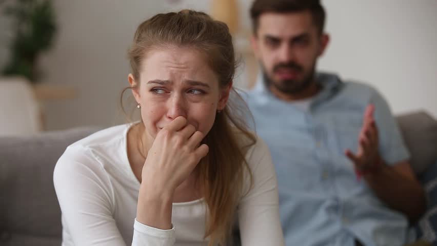 Couple quarrelling sitting on couch at home, focus on desperate girlfriend crying while boyfriend screams accusing her. Break up, unwanted pregnancy man insists on abortion, jealousy, conflict concept | Shutterstock HD Video #1028517155