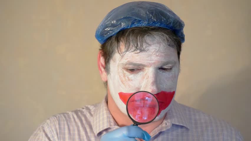 funny mime looks into a magnifier.portrait of a cheerful actor close up.modern visual art.