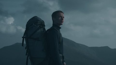 The man with a tourist backpack standing on the beautiful mountain