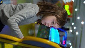 Vertical video. The girl solves the problem on the electronic device. A child at a children's playground in a shopping center.
