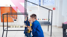 Children at the science center experimenting with Newton's cradle. The concept of physics. Museum of Science